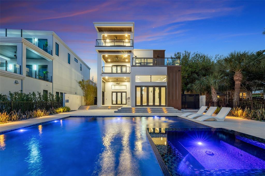 A modern three-story house with a swimming pool and spa at dusk — 1194 N PENINSULA AVENUE, NEW SMYRNA BEACH, FL