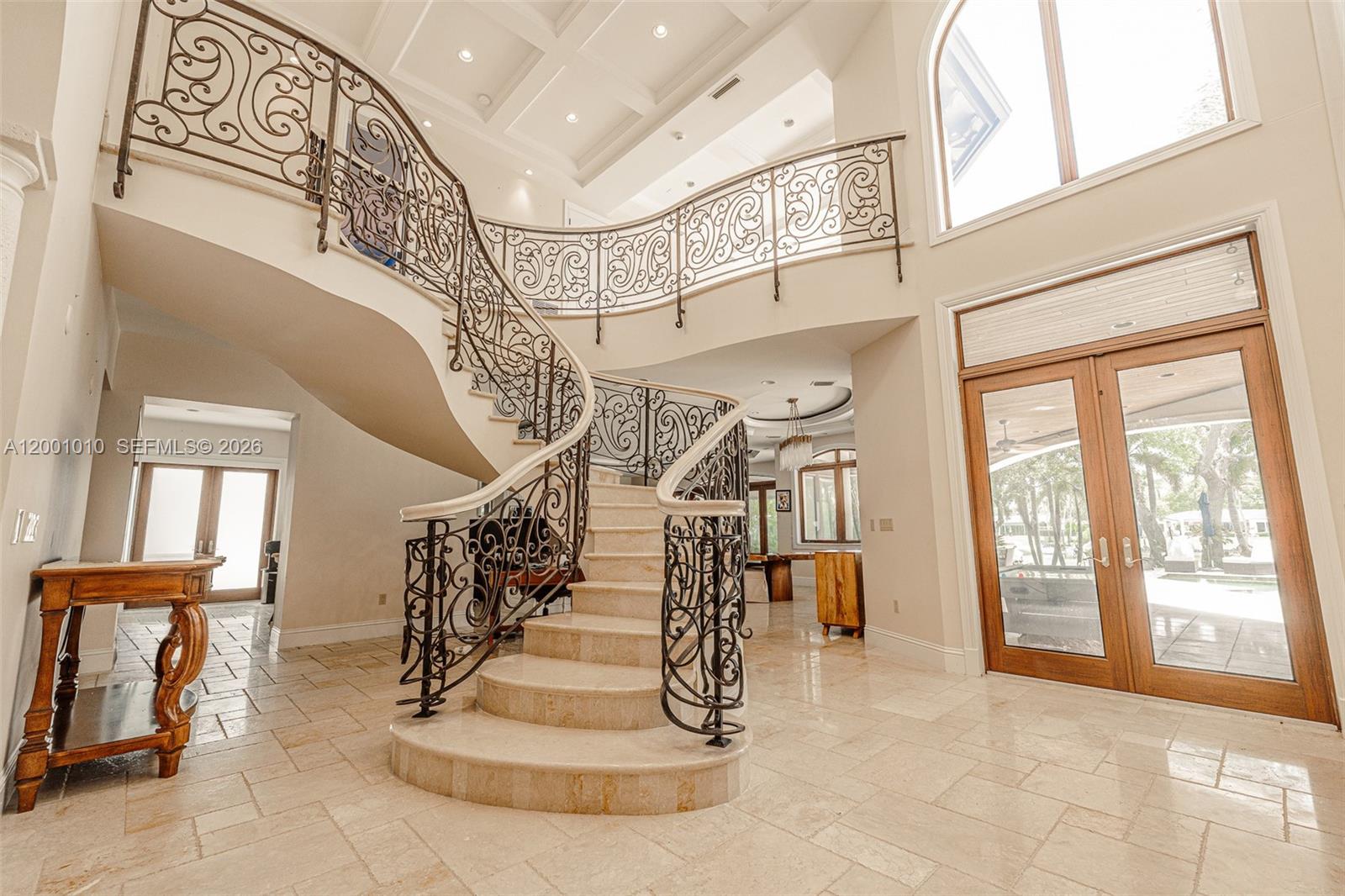A grand foyer features a curved stone staircase with ornate metal railings and tile flooring — 9240 SW 140th St, Miami FL 33176, MIAMI, FL