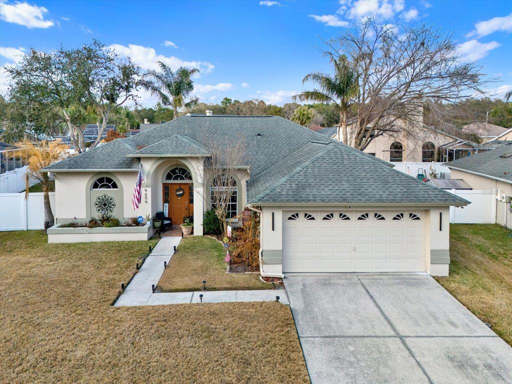 A single-story house with a beige stucco exterior, a green shingled roof, and a garage — 9656 FOX HEARST ROAD, TAMPA, FL