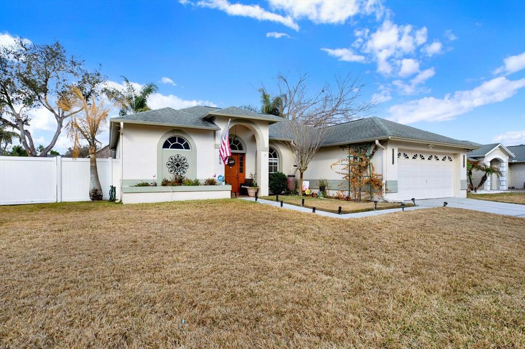A single-story house with a beige stucco exterior, a green roof, and a two-car garage — 9656 FOX HEARST ROAD, TAMPA, FL