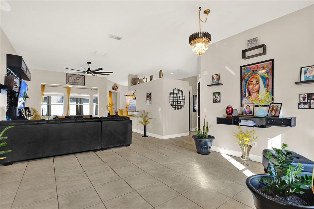 A spacious living room features tile flooring, a black sectional sofa, and a decorative wall display — 9656 FOX HEARST ROAD, TAMPA, FL