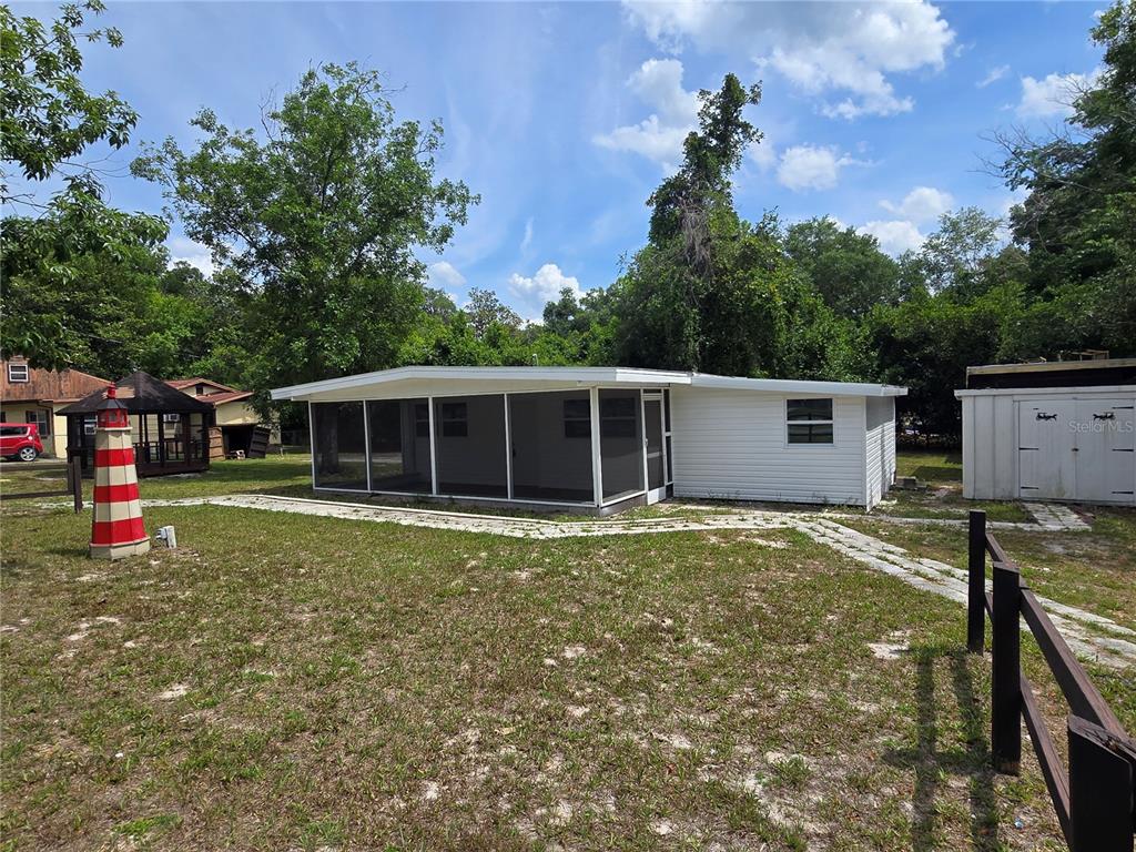 A white house with a screened-in porch, a decorative lighthouse, and a storage shed — 10566 E RABBIT LANE, FLORAL CITY, FL