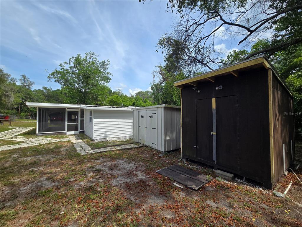 A backyard view shows a white house with a screened porch and two storage sheds — 10566 E RABBIT LANE, FLORAL CITY, FL