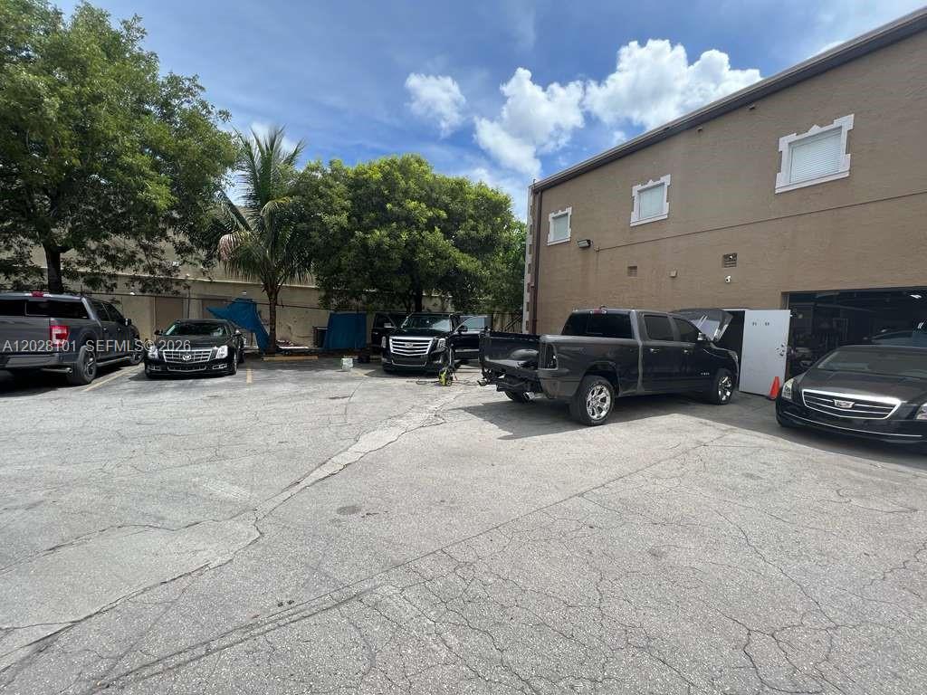 An exterior view shows a parking lot with several vehicles parked near a commercial building — 13690 SW 142nd Ave, Miami FL 33186, MIAMI, FL