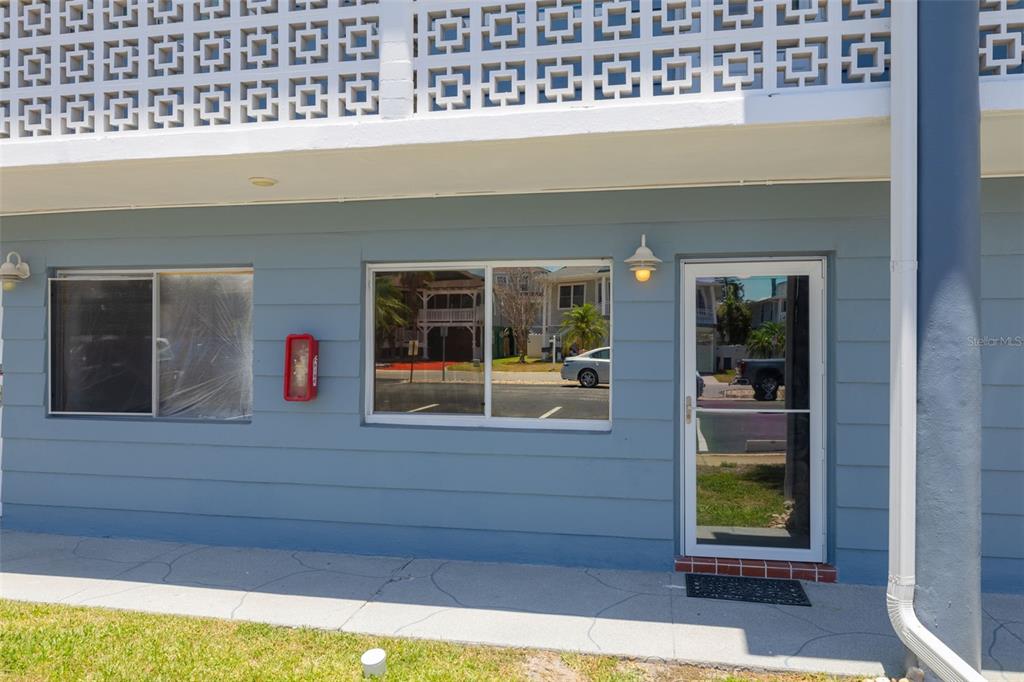 A blue exterior wall features a window, a door, and a decorative concrete block screen — 250 126TH AVENUE UNIT 104, TREASURE ISLAND, FL