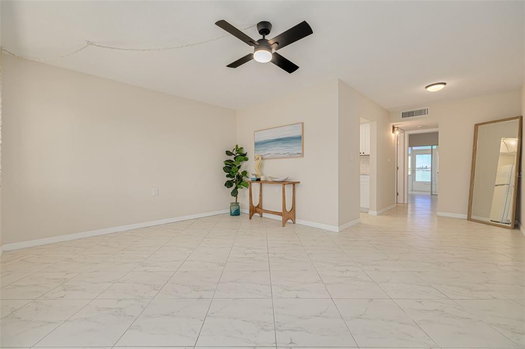 A living room with light-colored tile flooring, a ceiling fan, and a console table — 250 126TH AVENUE UNIT 104, TREASURE ISLAND, FL