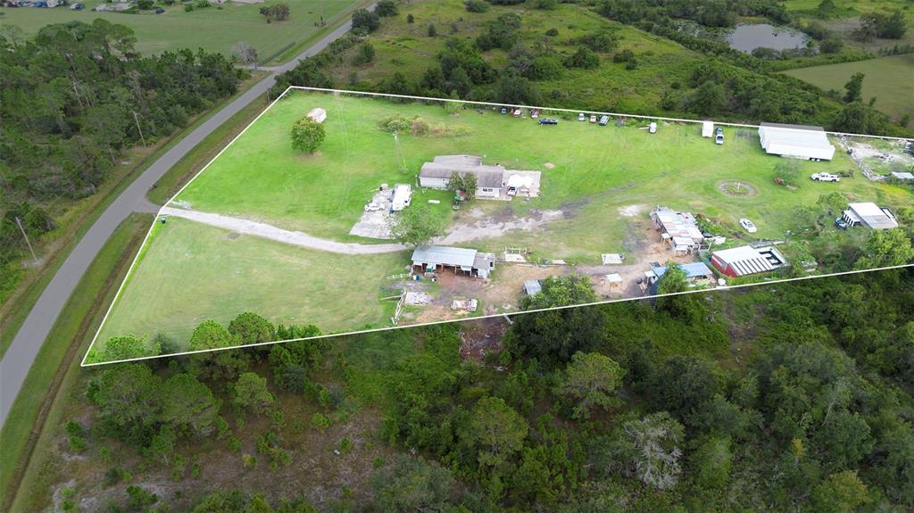 An aerial view shows a rural property with a house, outbuildings, and surrounding wooded land — 4250 HIGH PLAINS LANE, KISSIMMEE, FL