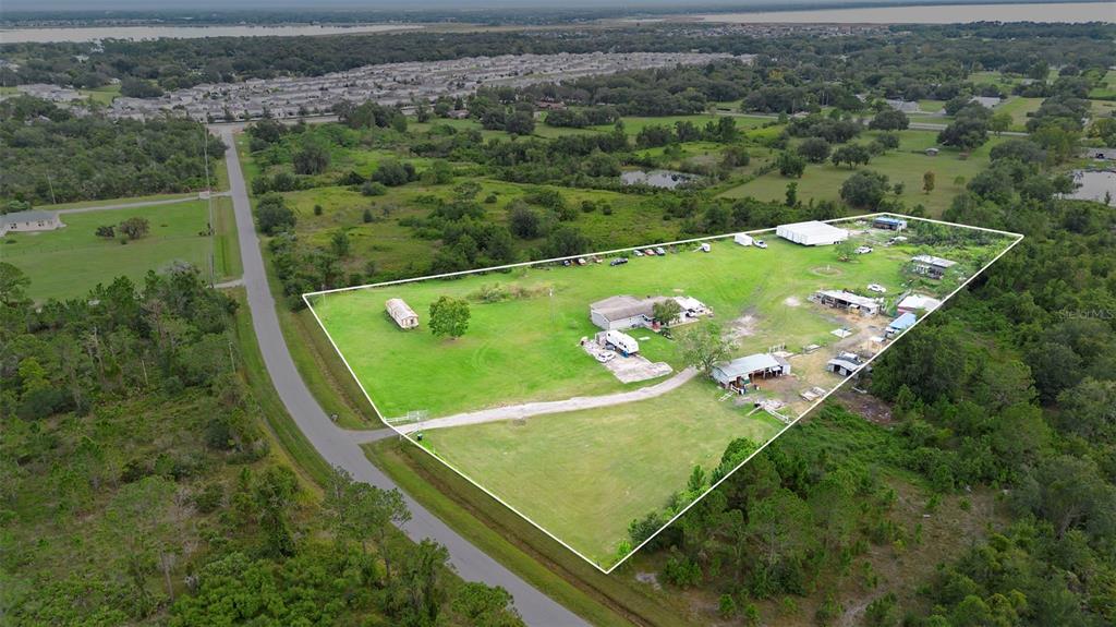 An aerial view shows a large, grassy lot with several outbuildings and a house — 4250 HIGH PLAINS LANE, KISSIMMEE, FL