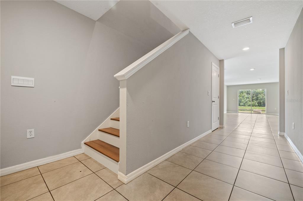 A hallway with tile flooring leads to a living area with sliding glass doors — 11722 WHITE WILLOW LANE, RIVERVIEW, FL