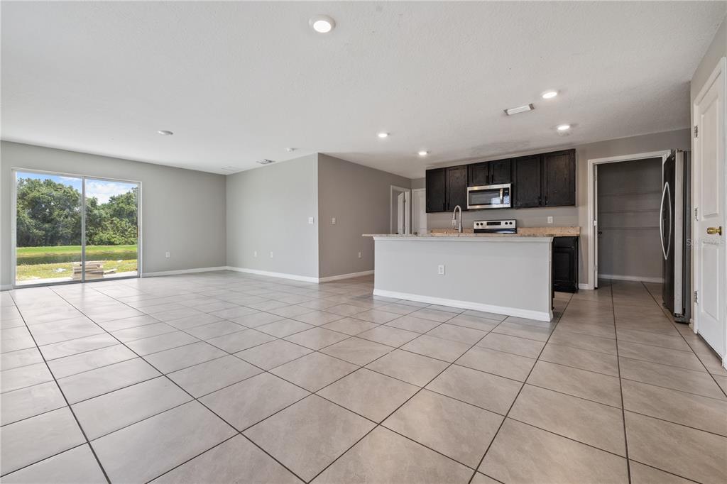 An open-concept kitchen and living area features light tile flooring and dark wood cabinets — 11722 WHITE WILLOW LANE, RIVERVIEW, FL