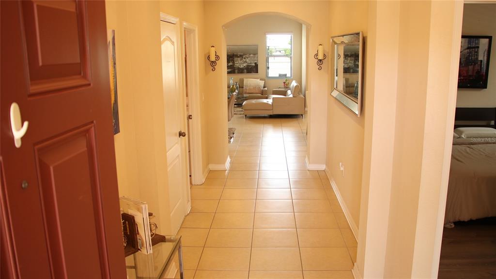 A tiled hallway leads from an entryway into a living room with light-colored furniture — 1429 CLEAR BROOK PLACE, ST CLOUD, FL