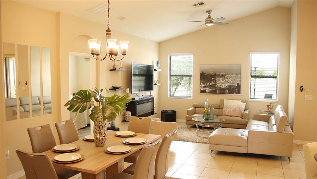 A dining area and living room with tile floors, a vaulted ceiling, and neutral walls — 1429 CLEAR BROOK PLACE, ST CLOUD, FL