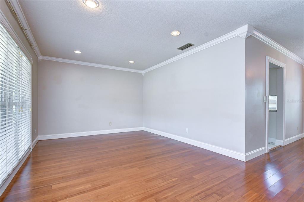 An empty room with light gray walls, hardwood floors, recessed lighting, and large windows — 4723 SOUTHBREEZE DRIVE, TAMPA, FL