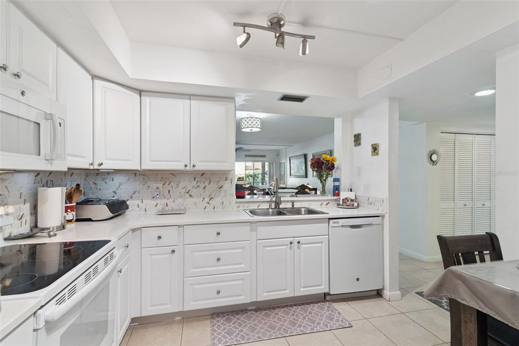 A kitchen with white cabinets, light countertops, a double sink, and a tiled backsplash — 530 CRANES WAY UNIT 107, ALTAMONTE SPRINGS, FL