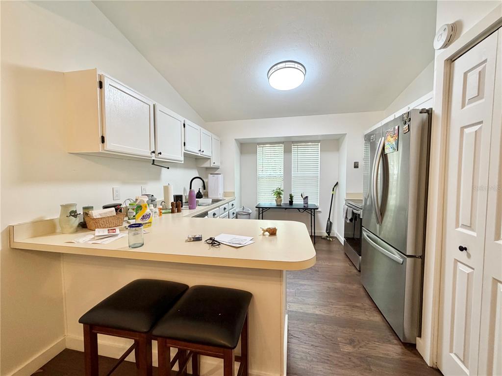 A kitchen features white cabinets, a breakfast bar with stools, and stainless steel appliances — 421 NW 48TH BOULEVARD, GAINESVILLE, FL