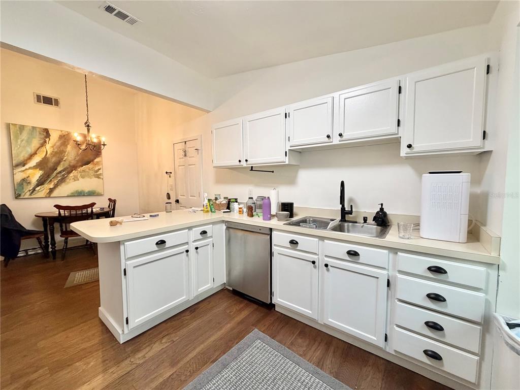 A kitchen with white cabinets, stainless steel dishwasher, and a breakfast bar — 421 NW 48TH BOULEVARD, GAINESVILLE, FL