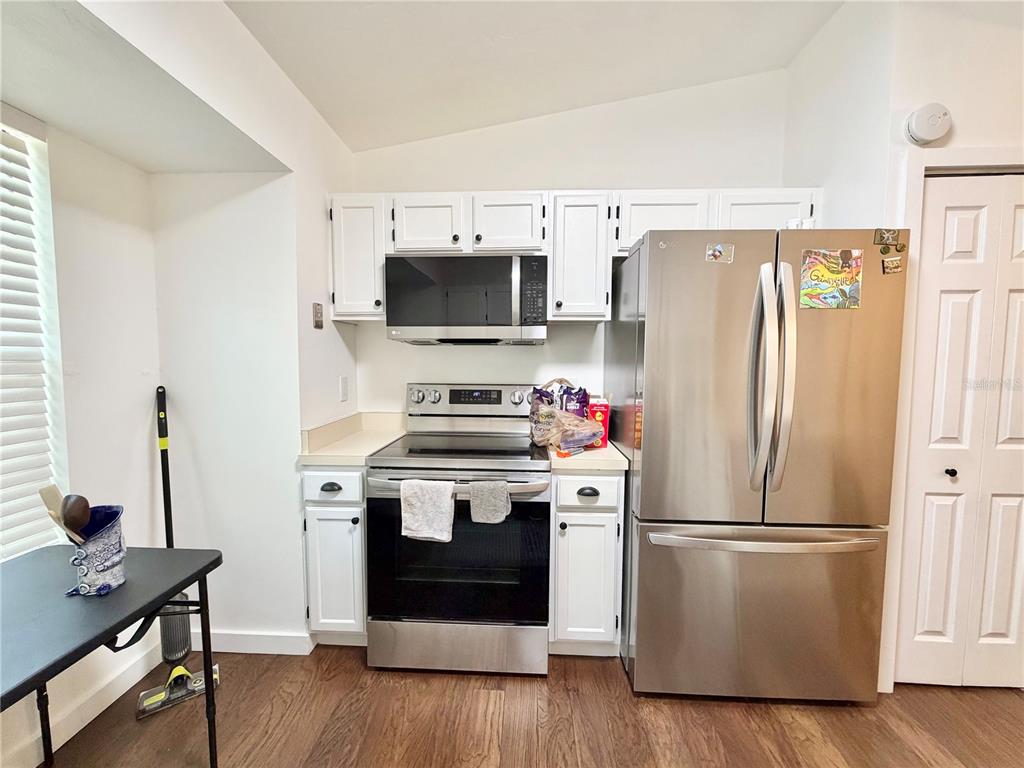 A kitchen features white cabinets, stainless steel appliances, and wood-look flooring — 421 NW 48TH BOULEVARD, GAINESVILLE, FL