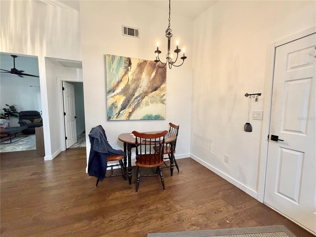 A dining area features a small round table, wooden chairs, a chandelier, and wall art — 421 NW 48TH BOULEVARD, GAINESVILLE, FL