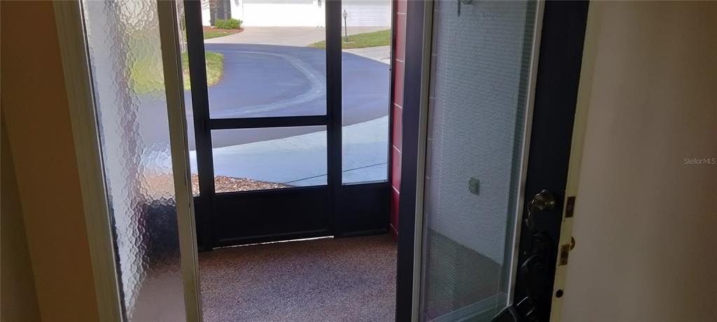 A view from an open doorway looking out onto a screened porch and driveway — 1812 ATRIUM DRIVE, SUN CITY CENTER, FL
