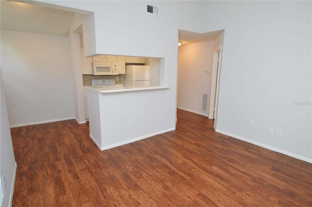 A room with wood-look flooring features a kitchen pass-through window and a breakfast bar — 8625 MALLARD RESERVE DRIVE UNIT 201, TAMPA, FL
