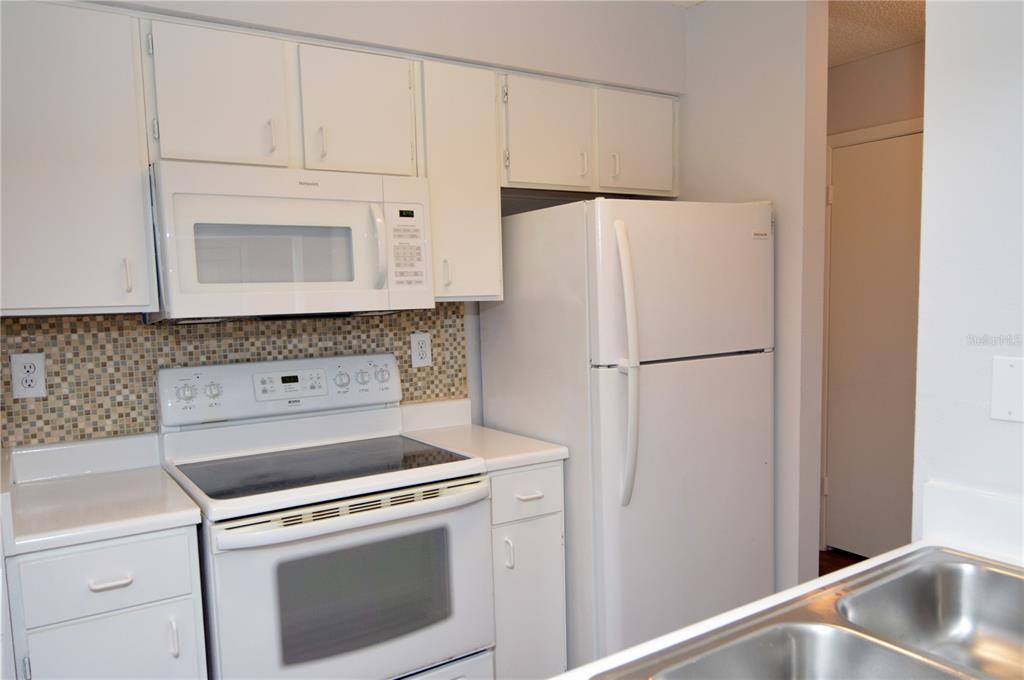 A kitchen features white cabinets, a white stove, a microwave, and a white refrigerator — 8625 MALLARD RESERVE DRIVE UNIT 201, TAMPA, FL