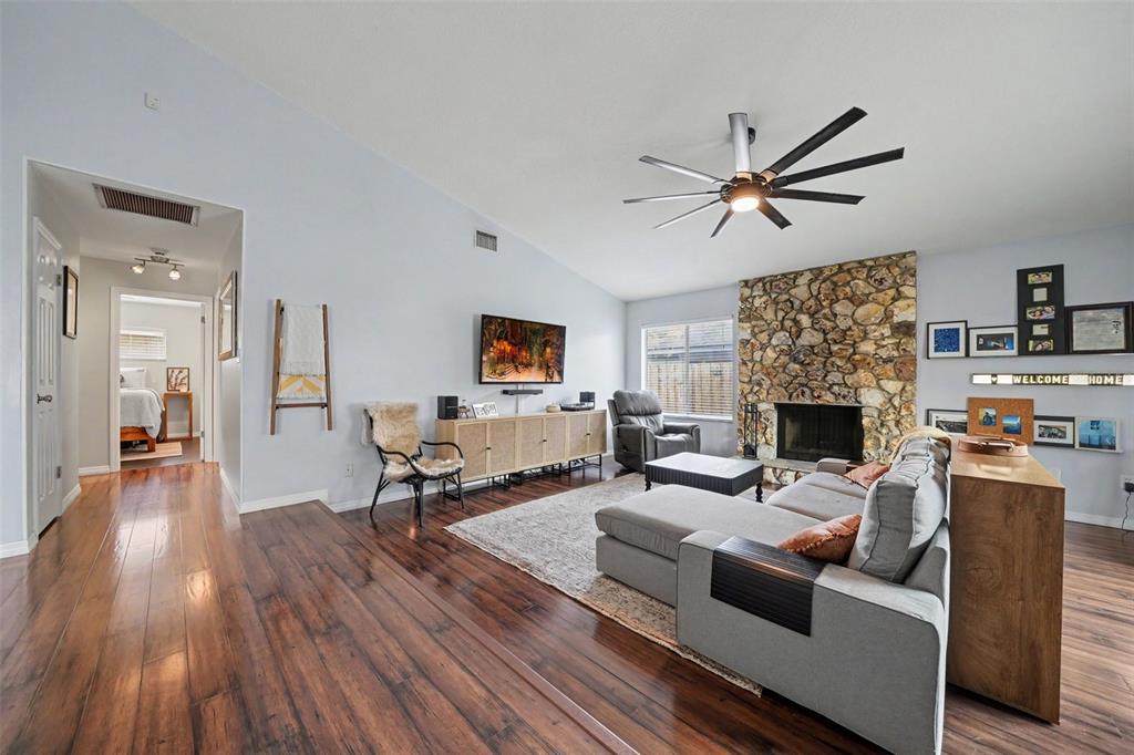 A living room with hardwood floors, a stone fireplace, and a gray sectional sofa — 144 SPOONHOUR DRIVE, CASSELBERRY, FL