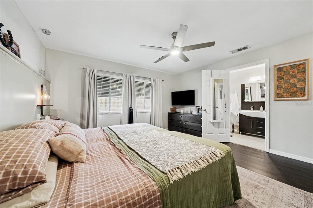 A bedroom with a bed, ceiling fan, dresser with a television, and an attached bathroom — 144 SPOONHOUR DRIVE, CASSELBERRY, FL