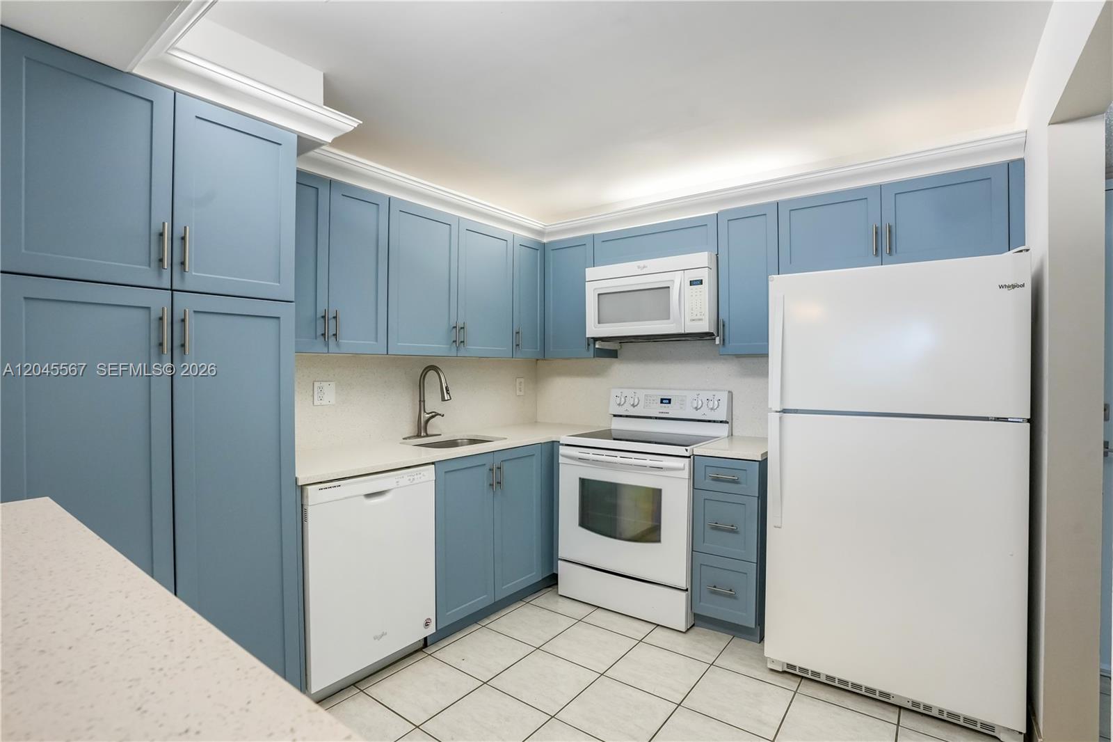 A kitchen features blue cabinets, white appliances, and light-colored countertops with tile flooring — 2301 S Ocean Dr # 1006, Hollywood FL 33019, HOLLYWOOD, FL