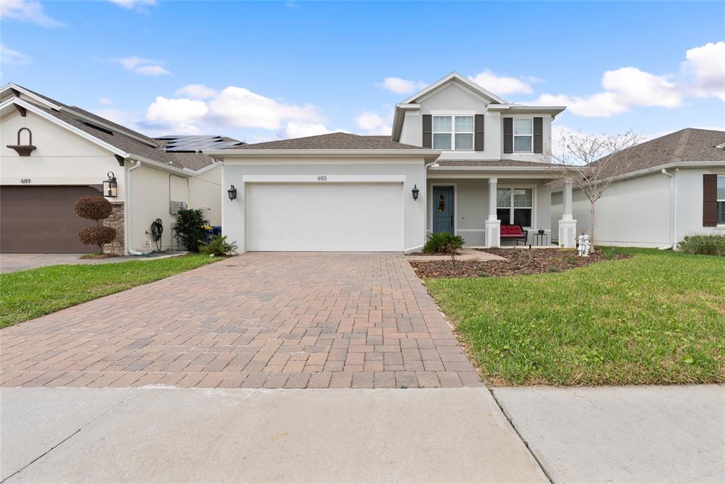 A two-story suburban house features a paved driveway, a two-car garage, and a covered porch — 693 BIG PINE AVENUE, MINNEOLA, FL