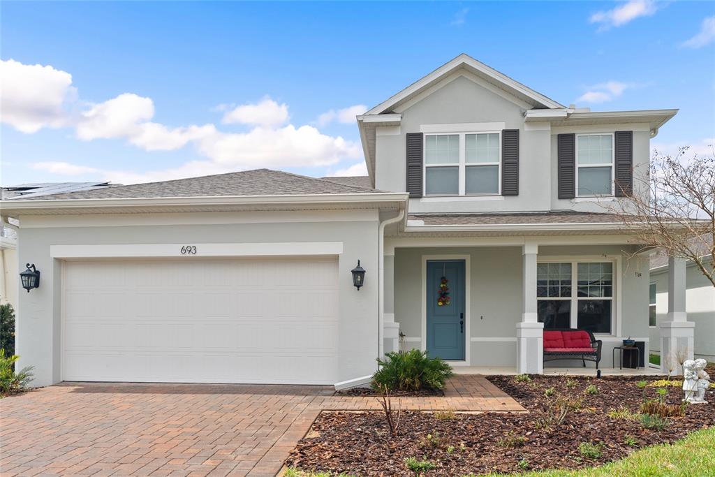A two-story house with a light gray exterior, a two-car garage, and a blue door — 693 BIG PINE AVENUE, MINNEOLA, FL