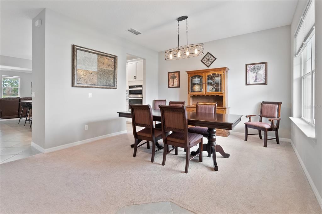 A dining room features a wooden table, chairs, a hutch, and a chandelier on carpet — 693 BIG PINE AVENUE, MINNEOLA, FL