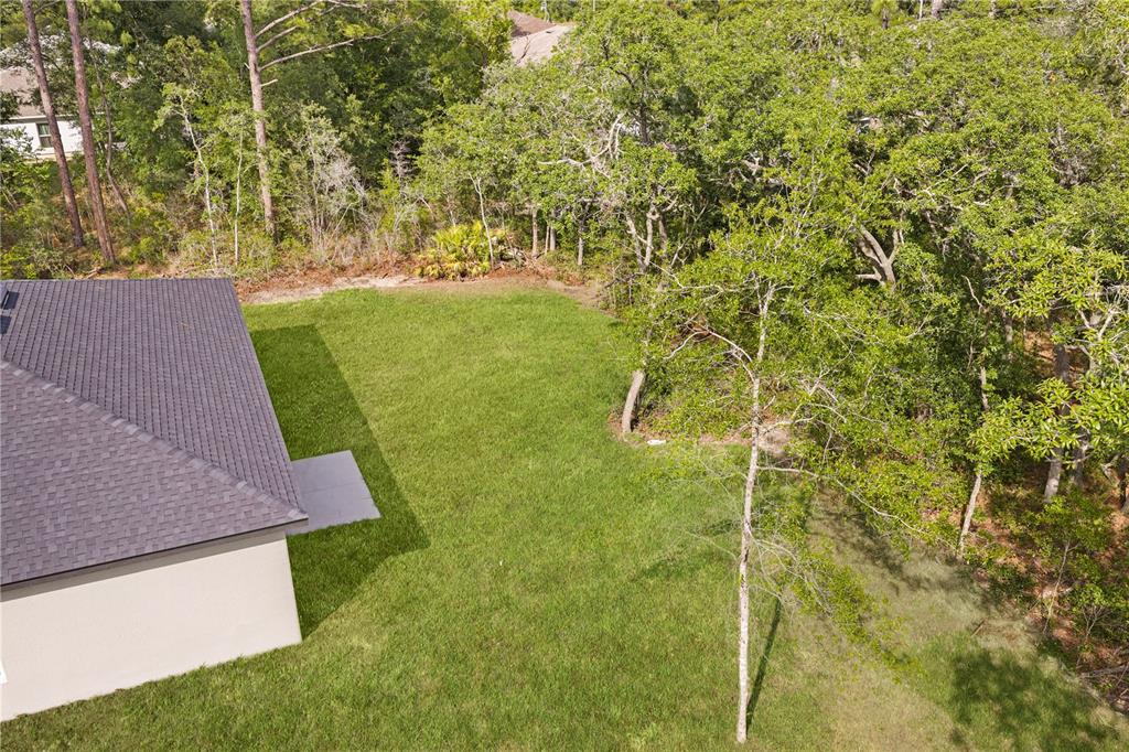 An aerial view shows a house corner with a dark shingled roof and a grassy backyard — 8555 N TROJAN DRIVE, CITRUS SPRINGS, FL