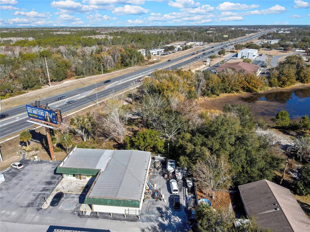 An aerial view shows a commercial building with a parking lot next to a highway — 0 COMMERCIAL WAY, SPRING HILL, FL
