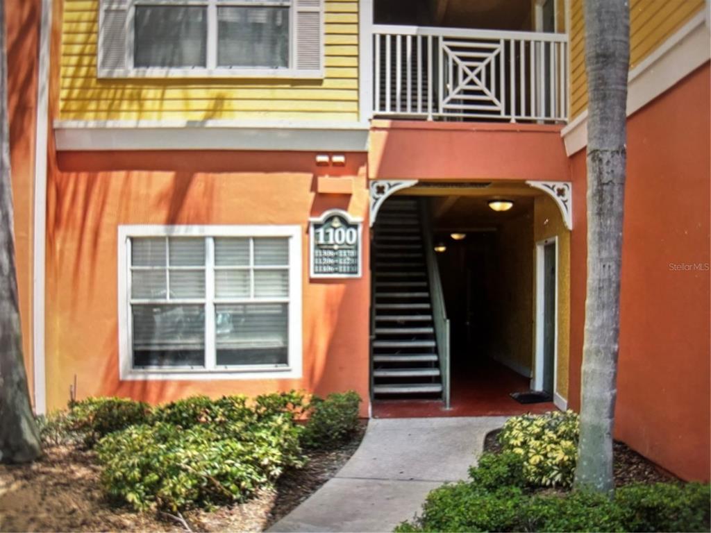 An exterior view of a multi-story apartment building with orange walls and a staircase entrance — 4207 S DALE MABRY HIGHWAY UNIT 11108, TAMPA, FL