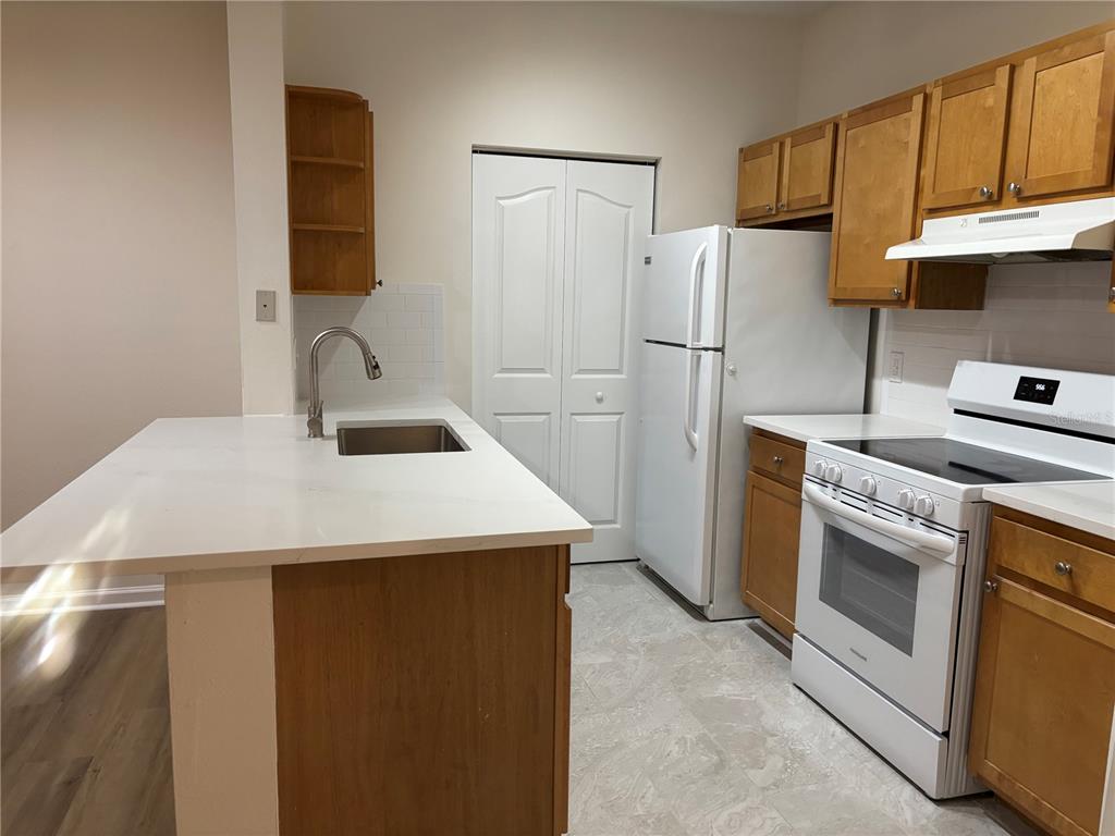 A kitchen features wood cabinets, white appliances, a breakfast bar, and light-colored flooring — 4207 S DALE MABRY HIGHWAY UNIT 11108, TAMPA, FL