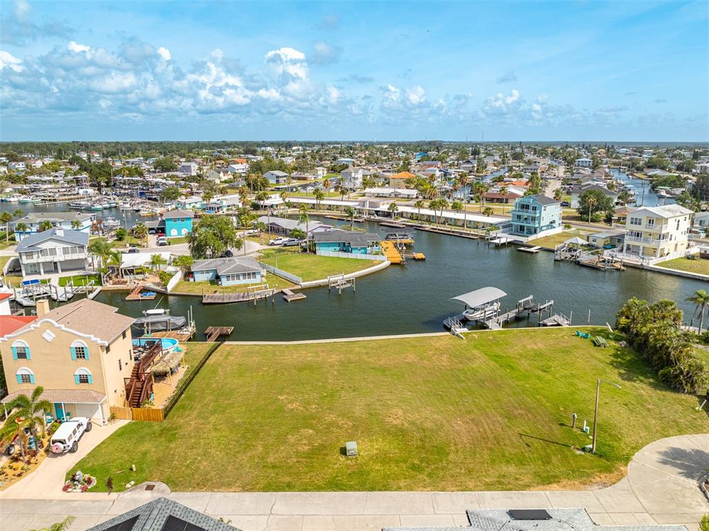 An aerial view shows a vacant waterfront lot next to a house with a boat dock — LOT 7 LOUISE COURT, HUDSON, FL