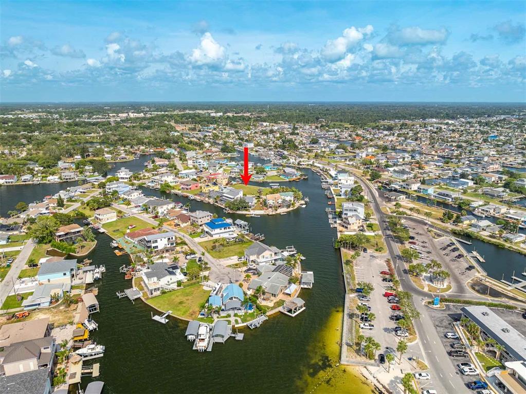 An aerial view shows waterfront homes and a vacant lot marked by a red arrow — LOT 7 LOUISE COURT, HUDSON, FL