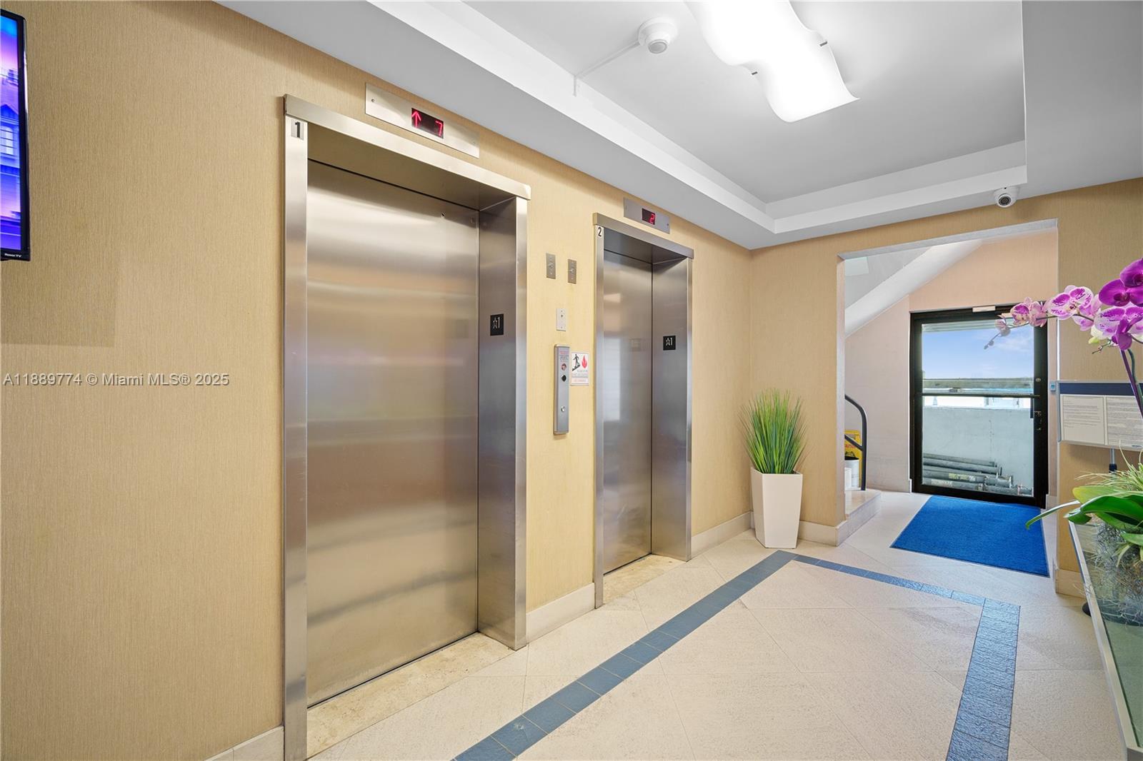 This elevator lobby features stainless steel doors, beige walls, and a tiled floor — 770 NE 69th St # 2H, Miami FL 33138, MIAMI, FL