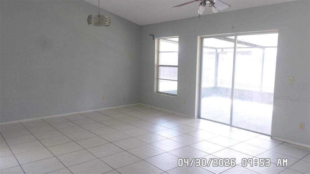 A living room features light blue walls, white tile flooring, and a sliding glass door — 2665 MILL RUN BOULEVARD, KISSIMMEE, FL