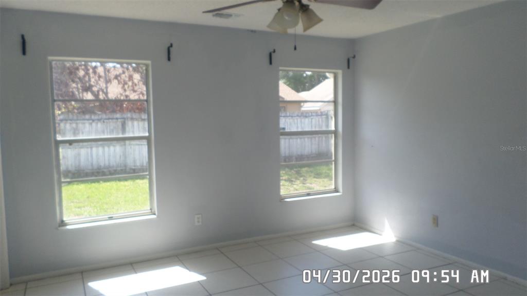 A room with light blue walls, white tile flooring, and two windows overlooking a yard — 2665 MILL RUN BOULEVARD, KISSIMMEE, FL