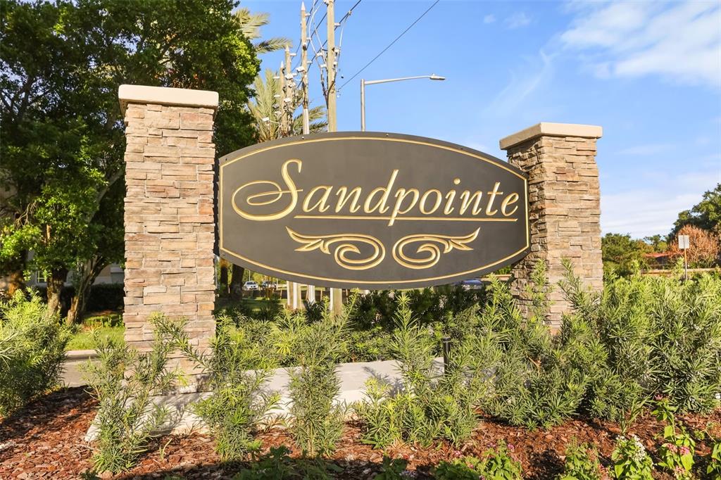 A stone-pillared monument sign displays the name Sandpointe in a landscaped outdoor setting — 8209 SANDPOINT BOULEVARD, ORLANDO, FL