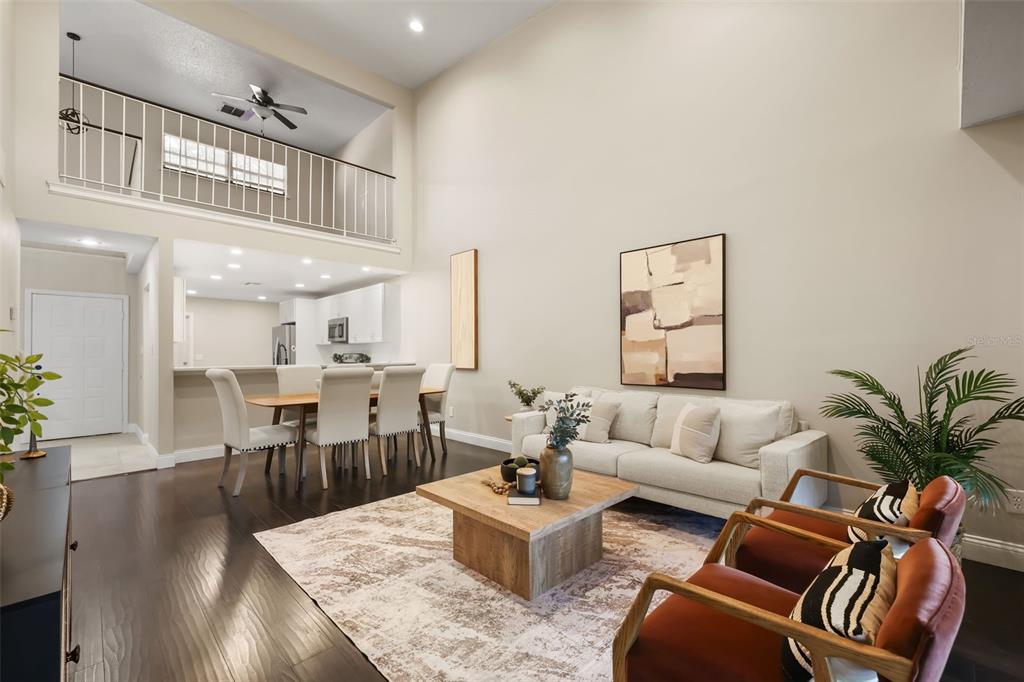 A living room with high ceilings, dark wood floors, and an open dining area — 8209 SANDPOINT BOULEVARD, ORLANDO, FL