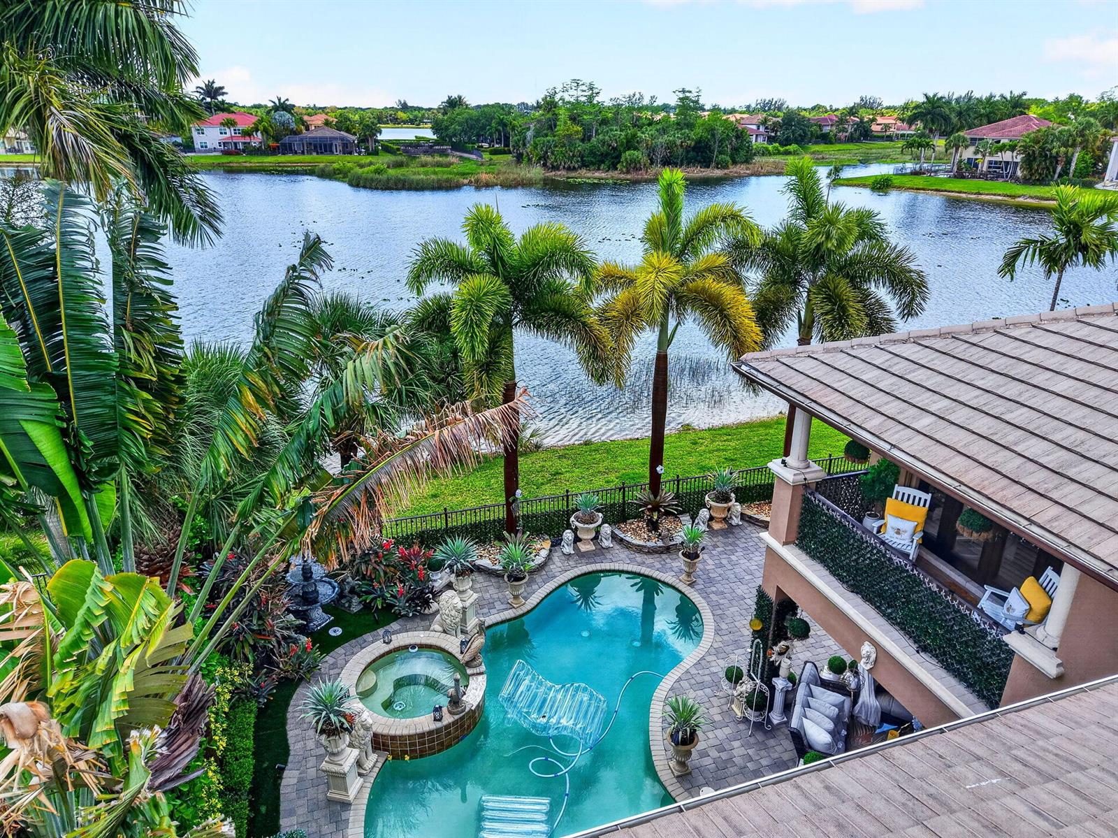 An elevated view of a backyard pool, hot tub, and patio overlooking a lake — 611 Edgebrook Lane, Royal Palm Beach FL 33411, ROYAL PALM BEACH, FL