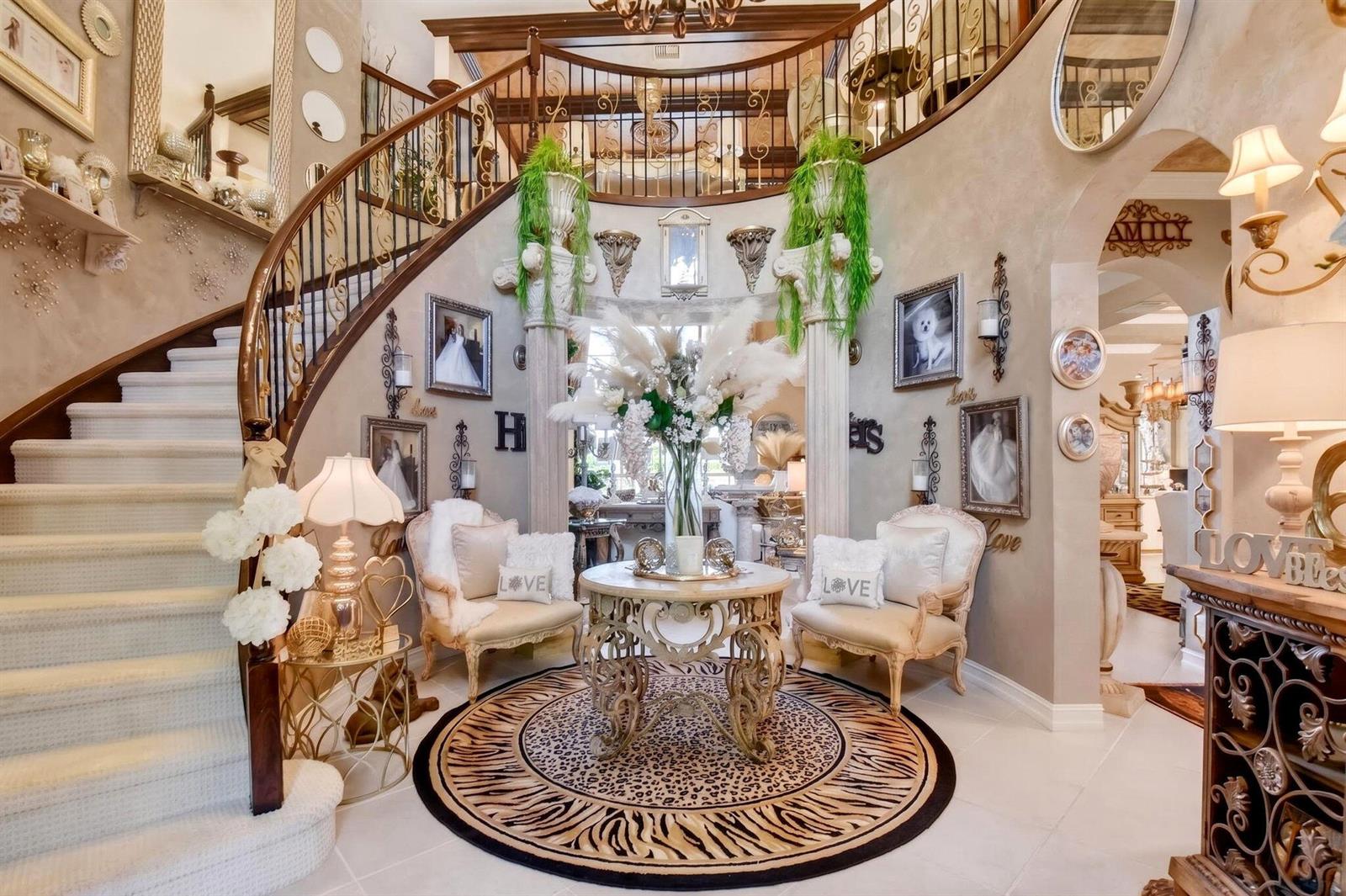 A grand foyer features a curved staircase, a central round table, and two accent chairs — 611 Edgebrook Lane, Royal Palm Beach FL 33411, ROYAL PALM BEACH, FL