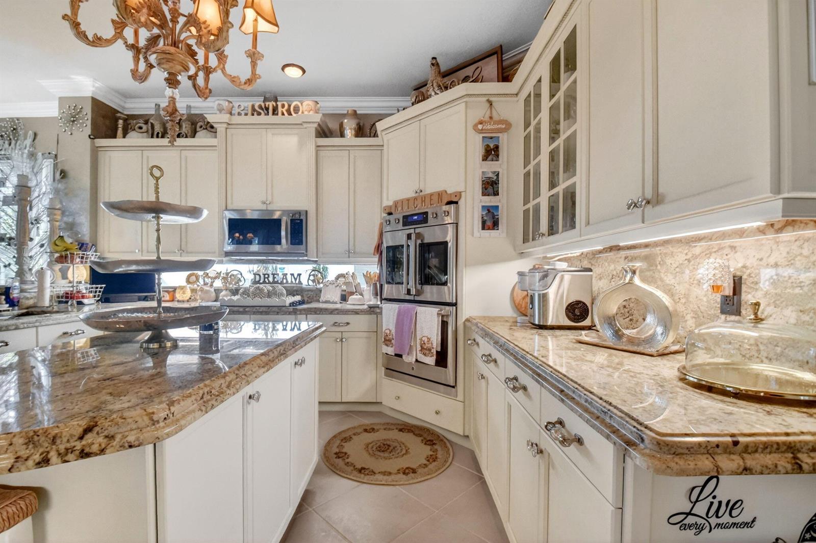 A kitchen features cream-colored cabinets, granite countertops, stainless steel appliances, and a central island — 611 Edgebrook Lane, Royal Palm Beach FL 33411, ROYAL PALM BEACH, FL