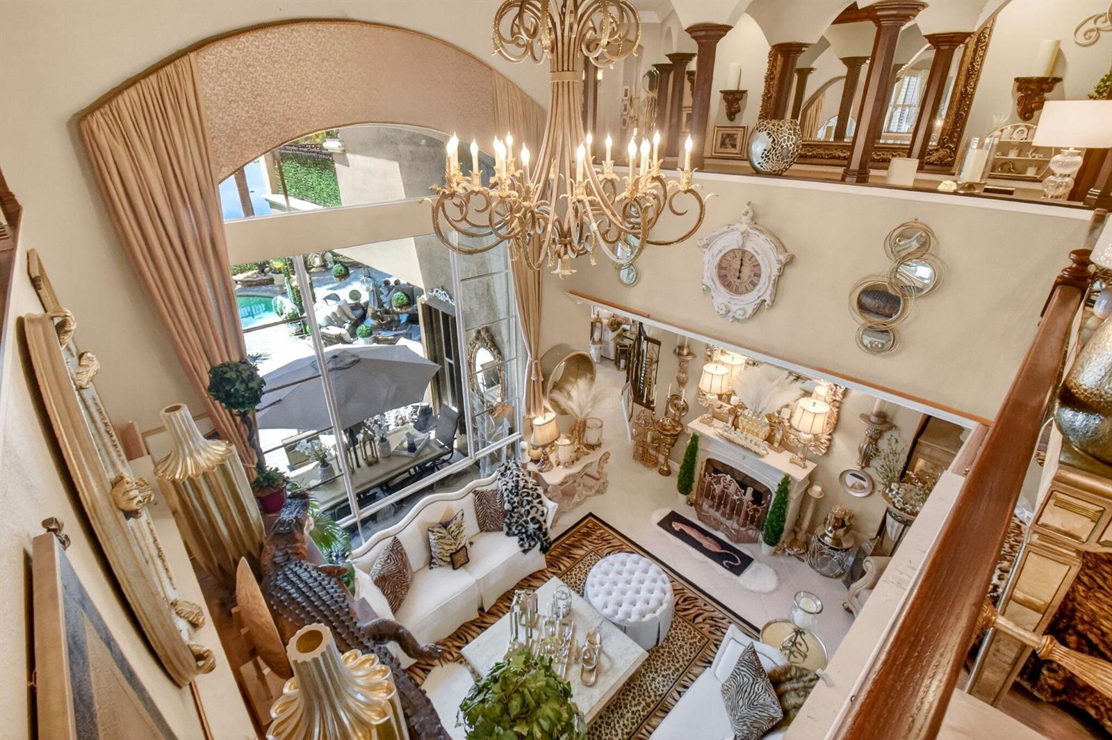 A high-angle view of a two-story living room featuring a large chandelier, fireplace, and patio — 611 Edgebrook Lane, Royal Palm Beach FL 33411, ROYAL PALM BEACH, FL