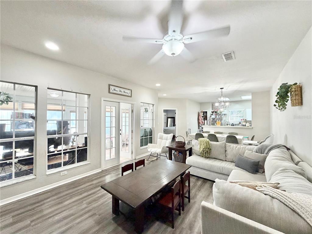 A living room with wood-look flooring, a ceiling fan, a dining table, and a sectional sofa — 7090 NW 52ND TERRACE, GAINESVILLE, FL