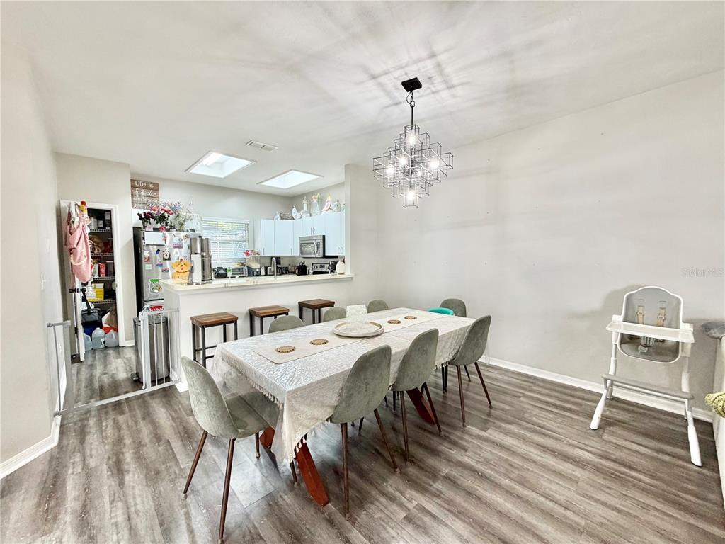 A dining area with a rectangular table, six chairs, and a chandelier, adjacent to a kitchen — 7090 NW 52ND TERRACE, GAINESVILLE, FL