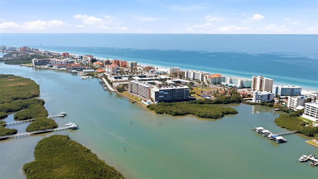 Aerial view of a coastal resort area with multi-story buildings, mangroves, and a waterway — 19451 GULF BOULEVARD UNIT 203, INDIAN SHORES, FL