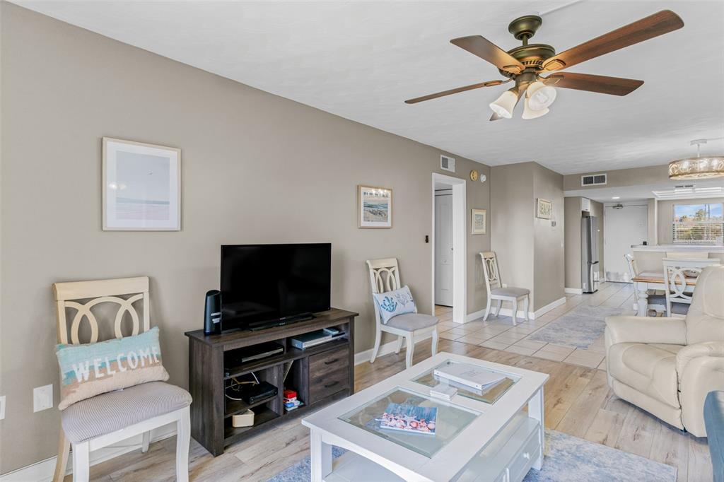 A living room features a ceiling fan, a television on a console, and light flooring — 19451 GULF BOULEVARD UNIT 203, INDIAN SHORES, FL